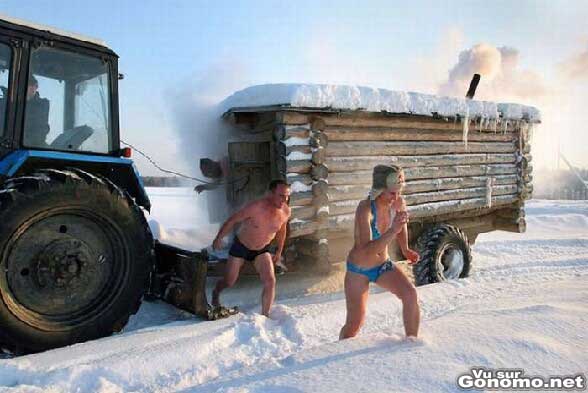 Un sauna mobile en bois traine par un tracteur dans la neige