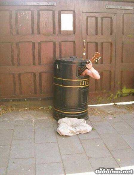 Un musicien de rue joue de la guitare cache dans une poubelle ??