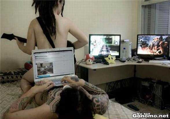 Gamer sex : un bon couple de geek au lit avec le pc portable et la fille qui joue a Guitar Hero