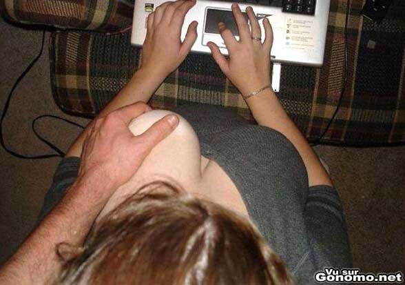 Une geekette topless sur son pc se fait peloter les seins par un mec derriere elle :p