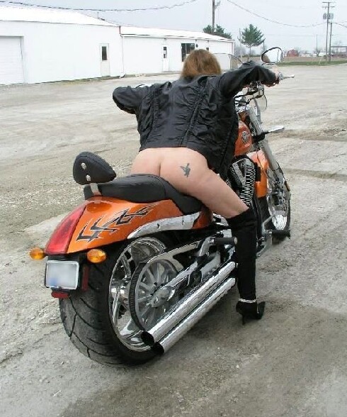 Motarde nue : une femme a poil sur sa Harley, les fesses a l air, le blouson et les bottes en cuir ...