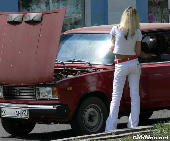 Une belle blonde fashion tout en blanc en panne a cote de sa voiture