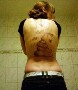 Une femme avec le tattoo d une grosse crotte dans le dos et les mouches qui vont avec :s